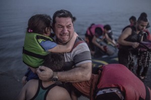 A Syrian refugee from Deir Ezzor, holding his son and daughter, breaks out in tears of joy after arriving via a flimsy inflatable boat crammed with about 15 men, women and children on the shore of the island of Kos in Greece, Aug. 15, 2015. *ON EMBARGO UNTIL AUGUST 27, 2015.* *** Local Caption *** 14706734